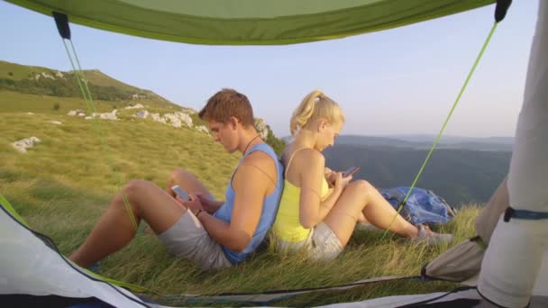 Κοντινό πλάνο Νεαρό ζευγάρι εθισμένο στα smartphones γραπτών μηνυμάτων κατά τη διάρκεια ενός ταξιδιού πεζοπορίας — Αρχείο Βίντεο