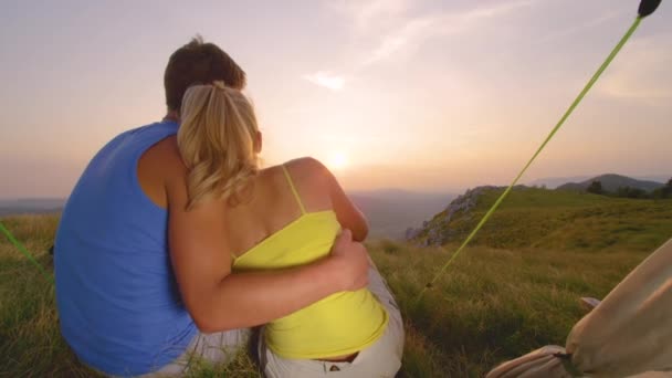 SLOW MOTION: Jovens caminhantes se abraçam na frente de sua tenda e assistem ao pôr do sol . — Vídeo de Stock