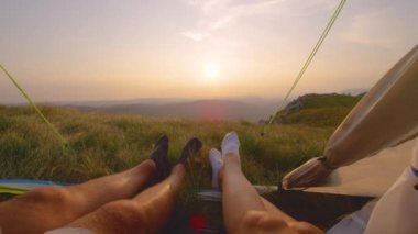 Yakın plan: bir çift çorap içinde çadırda yatıyor ve altın manzarayı izliyorlar..