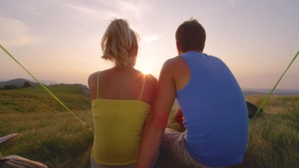 ZAMKNIJ SIĘ: Para przytulająca i oglądająca zachód słońca podczas wędrówki. — Wideo stockowe