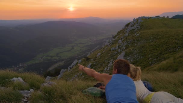 スローモーション:日没時に絵のように美しい山々を観察するアクティブな女性と男性. — ストック動画