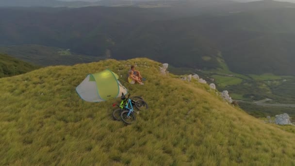 DRONE: Flying around active couple sitting by their tent and watching the sunset — Stock Video