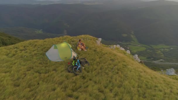 DRONE: Volando alrededor de una pareja activa sentada junto a su tienda y viendo la puesta de sol — Vídeo de stock