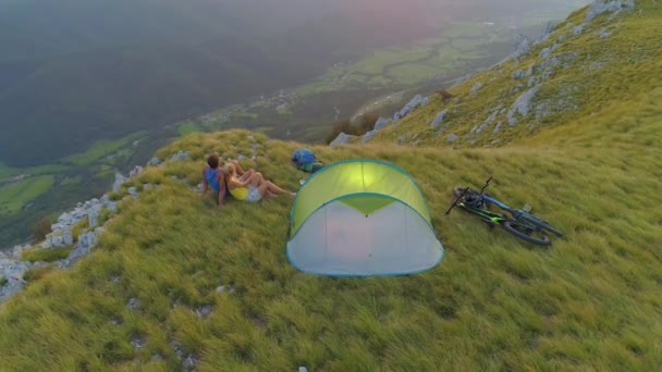 AERIAL: Létání nad bezstarostný turistický pár pozorování večerní krajiny. — Stock video