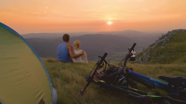 FECHAR UP: Casal desportivo sentado no abraço do outro e observando o pôr do sol — Vídeo de Stock