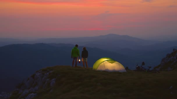Slow Motion: Ett bekymmerslöst par talar vid sitt tält en kall sommarkväll. — Stockvideo