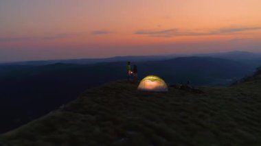 DRONE: Couple watching the sunrise during a fun mountain biking trip in Alps.