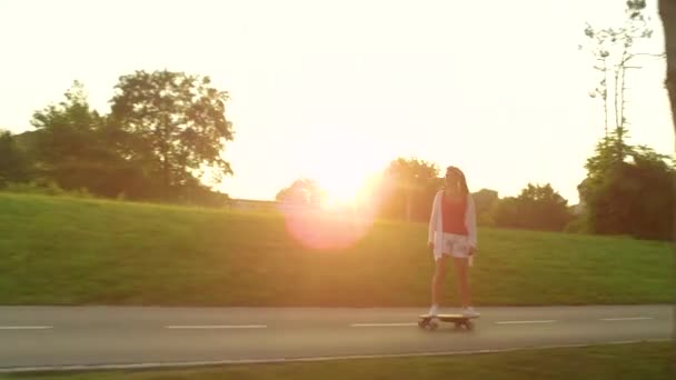 SUN FLARE:気をつけてください晴れた朝に彼女のe-longboardに乗る女性スケートボーダー. — ストック動画