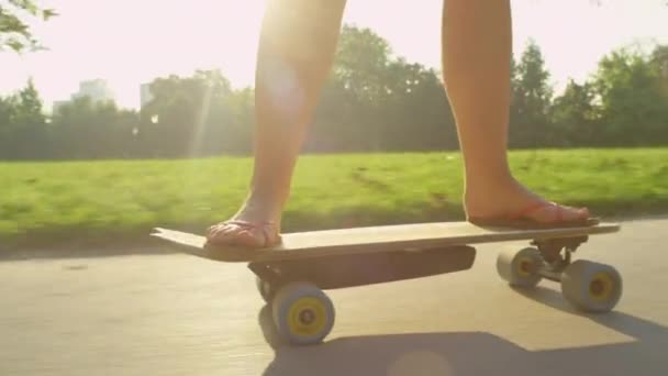 Nahaufnahme: Unerkennbar aktive Frau skatet durch den ruhigen, sonnenbeschienenen Park. — Stockvideo