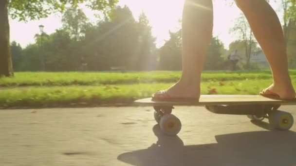 Slow Motion: Parkta güneşli bir bahar gününde parmak arası terlik giyen sporcu kız paten kayıyor. — Stok video