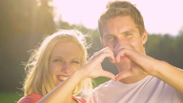 PORTRAIT:愛らしいカップルは、屋外の日付の間に指で心の形を作ります. — ストック動画