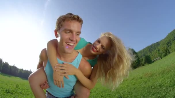 SLOW MOTION: Handsome Caucasian man gives cheerful girlfriend a piggyback ride. — Stock Video