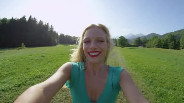スローモーション:空の牧草地で回転しながら豪華な若い女性の笑顔. — ストック動画