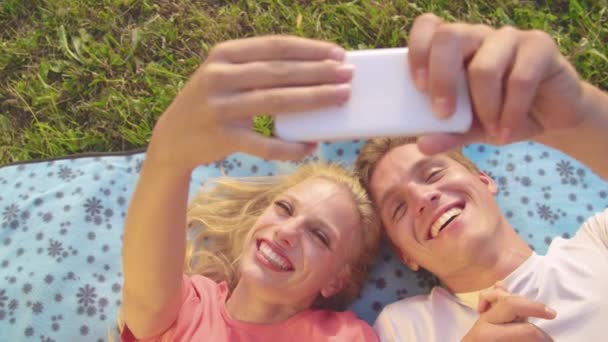 CERRAR Feliz mujer y novio sonrisa y apuntar al teléfono mientras toma selfies — Vídeos de Stock