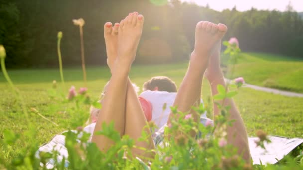 スローモーション:男と女は牧草地に横たわって、楽しい彼らの裸の足を蹴り — ストック動画