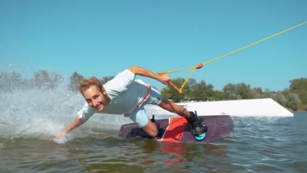 TEMPO ATTENZIONE: Sorridente wakesurfer cavalcando nel parco degli impianti di risalita in una giornata di sole . — Video Stock