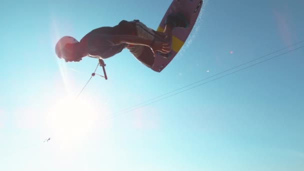 LENS FLARE: Happy wakesurfer faz um truque legal enquanto voa sobre a câmera — Vídeo de Stock