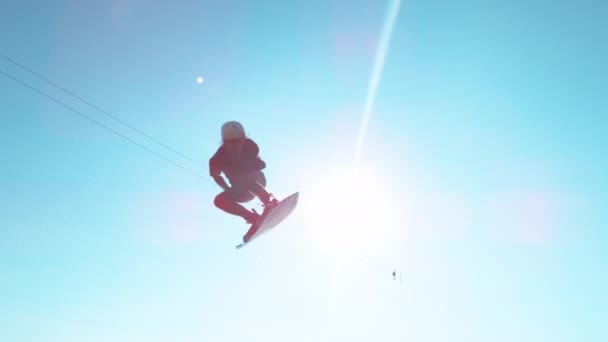 LENS FLARE: Athletic man spinning in the air while wakesurfing on the lake. — Stock Video