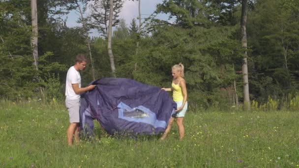 Jong stel werkt samen om een tent op te zetten tijdens een leuk kampeeravontuur — Stockvideo