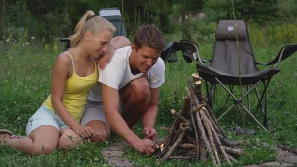 Slow Motion: Gelukkige man en vrouw die een kampvuur aansteken tijdens een kampeertocht. — Stockvideo