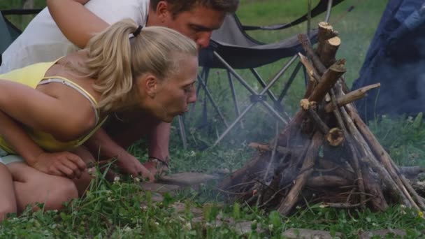 Slow Motion: Jongeman en vriendin blaast bij het aansteken van een vuur aan te steken. — Stockvideo
