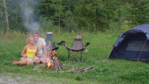 Copy Space: Leende par camping i den lugna skogen sitter vid lägerelden. — Stockvideo