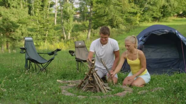 年轻女人在和男朋友准备篝火时试图击退昆虫. — 图库视频影像