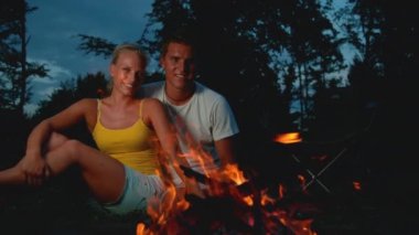 PORTRAIT: Gorgeous woman looking at camera while cuddling with boyfriend by fire