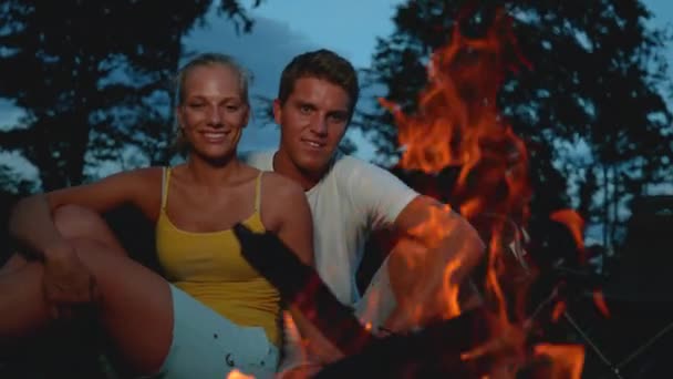 CLOSE UP: Cheerful Caucasian couple sitting by the campfire on a cold night. — Stock Video