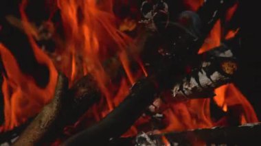 Zaman Yeniden Haritası: Turuncu alevlerin kamp ateşinde dalları yutan sinematik görüntüleri.