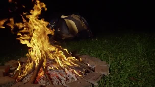 MOTION LENT, FERMER : Grand feu de joie fournissant lumière et chaleur près de la tente vide . — Video