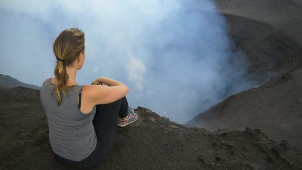 FECHAR UP: Jovem viajante senta-se na borda da cratera do Monte Yasur em Vanuatu. — Vídeo de Stock