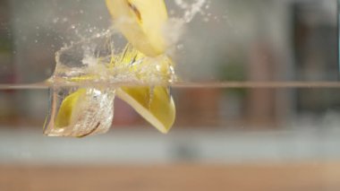 Slow Motion, Macro: Dilimlenmiş altın gibi lezzetli elma cam suya düşer.