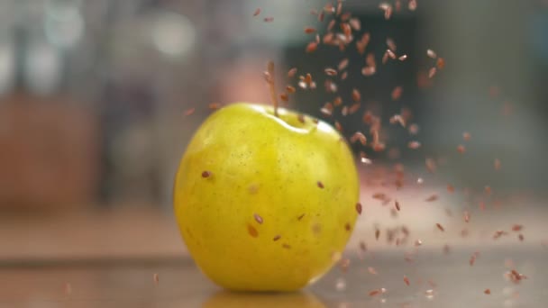 MACRO, DOF: Winzige braune Leinsamen fallen aus der Luft auf den gelben Apfel. — Stockvideo