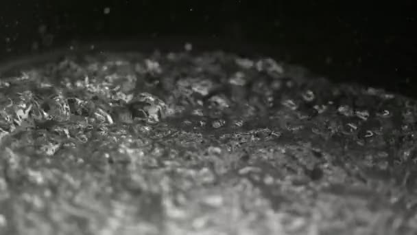 MACRO, DOF: Pequeñas gotas de agua salen volando de la sartén de agua hirviendo — Vídeos de Stock