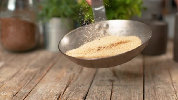 SLOW MOTION: Breadcrumbs fall on the table as female chef mixes them in hot pan. — Stock Video