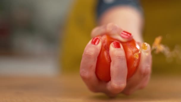 Slow Motion: Organische tomaat explodeert in de hand van een vrouwelijke chef als ze knijpt. — Stockvideo