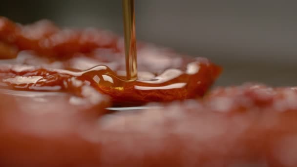 Slow Motion: Flurry skott av välsmakande olivolja stänk över de härdade tomaterna. — Stockvideo