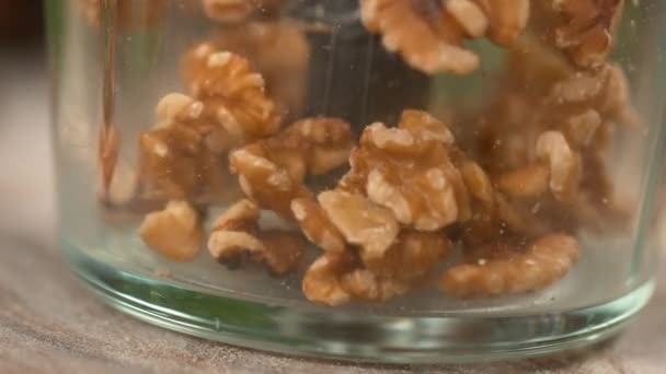 MACRO: Lekkere walnotenpitten stuiteren rond de plastic container van een blender. — Stockvideo