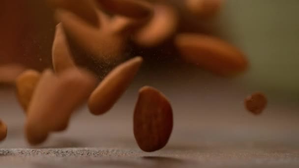 MOCIÓN LENTA: Nueces de almendras sanas caen del cielo y rebotan sobre la mesa . — Vídeo de stock