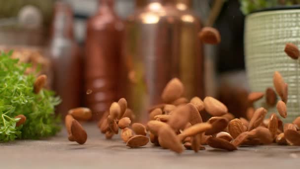 MOTION LENT : Des amandes brunes rôties savoureuses tombent et se dispersent autour de la table . — Video