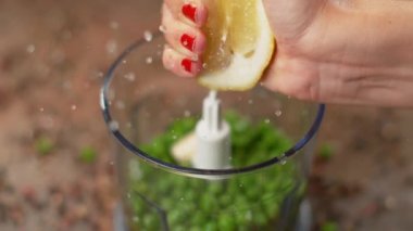 Kadın aşçı organik limonu çiğ bezelye dolu bir miksere sıkıştırıyor..