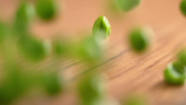 Lassú mozgás, MACRO, DOF: Nyers hazai zöld borsó pattogó le a fa asztal. — Stock videók