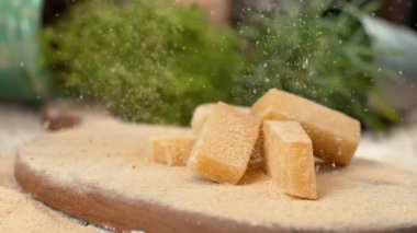 Parmesan taneleri tahtanın üzerindeki peynir küplerinin üzerine düşer..