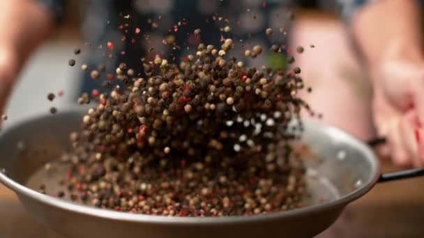 MACRO, DOF: Peppercorns volando alrededor de la cocina mientras la mujer los asa en una sartén . — Vídeos de Stock