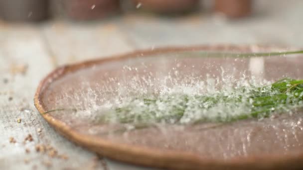 MACRO: краплі води розбризкують дерев'яний стіл після того, як цибуля впаде в тарілку . — стокове відео