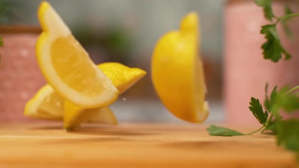 MACRO, DOF : Des morceaux de citron bio tombent et rebondissent sur la surface en bois . — Video