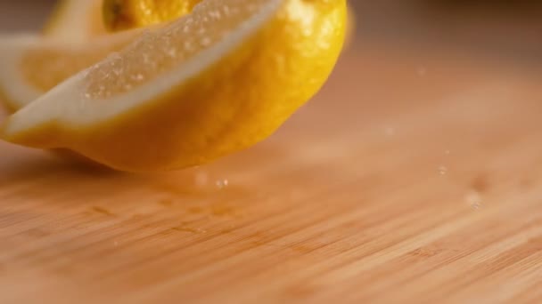 MACRO : Des quartiers de citron jaune vif parfumés tombent sur la planche à découper en bois . — Video