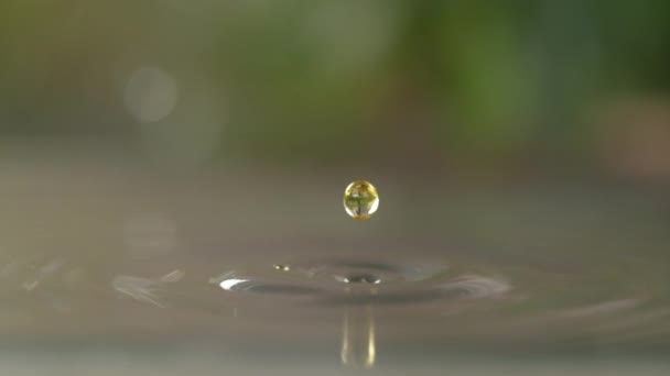 MACRO, DOF: Żółta kropla oleju słonecznikowego wpada do zlewu pełnego wody. — Wideo stockowe