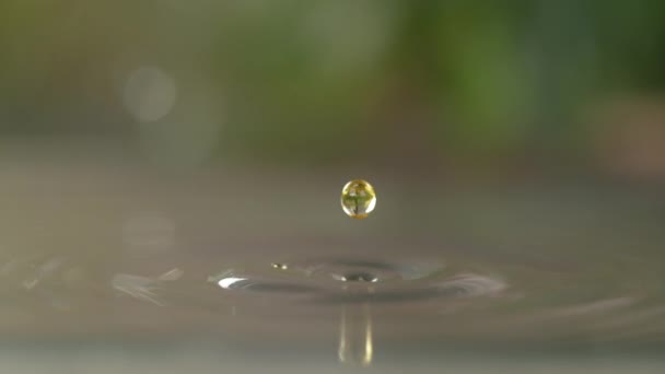 MACRO, DOF: Gele druppel zonnebloemolie valt in een gootsteen vol water. — Stockvideo